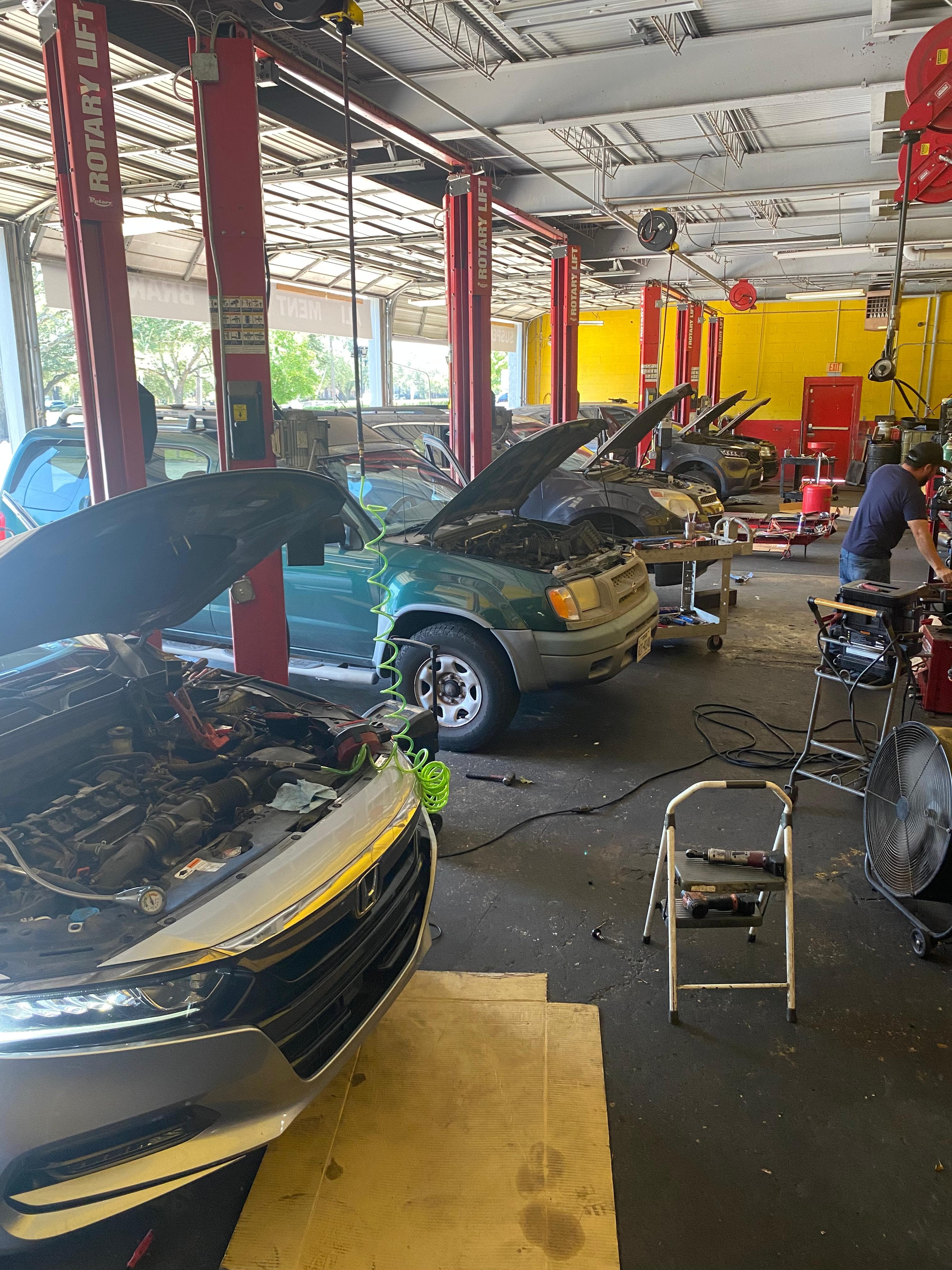 Piso de taller con varios vehículos en servicio sobre elevadores en Faktor Auto Repair